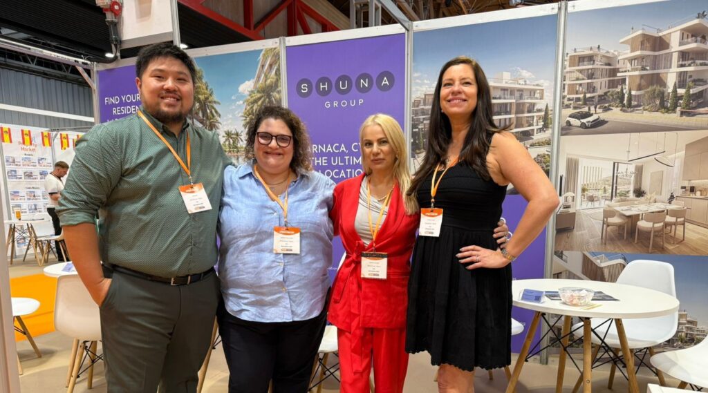 Real estate team posing together at a property exhibition booth promoting buying property in Cyprus.