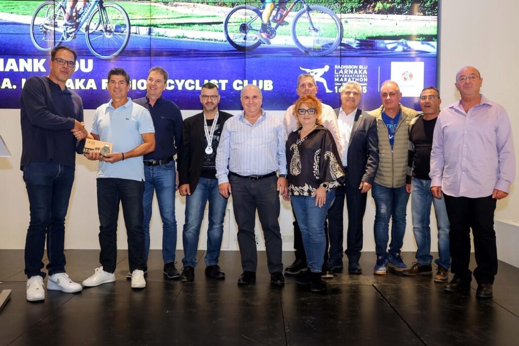Group of organizers and supporters standing on stage at a Cyprus charities recognition event celebrating contributions to charitable and cycling initiatives